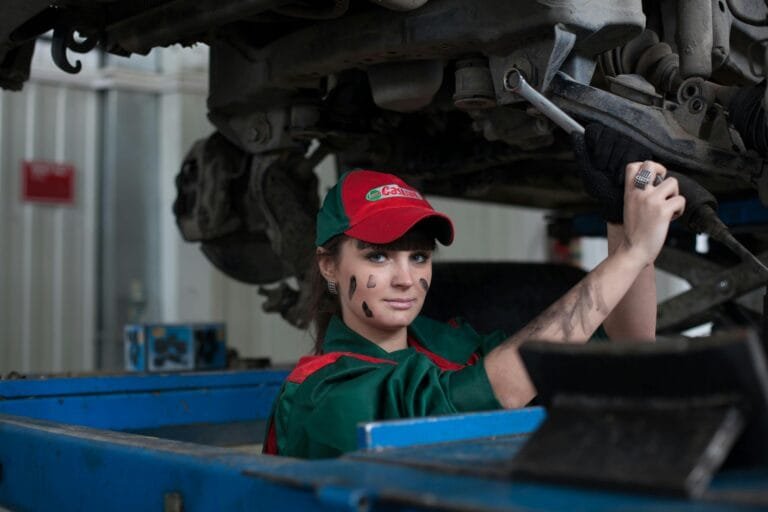 Female mechanic maintaining a car in an auto repair shop showcasing skill and concentration